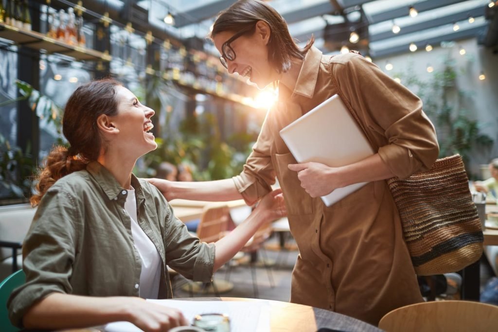 Two women at a sunlit table talking through self-employed retirement savings