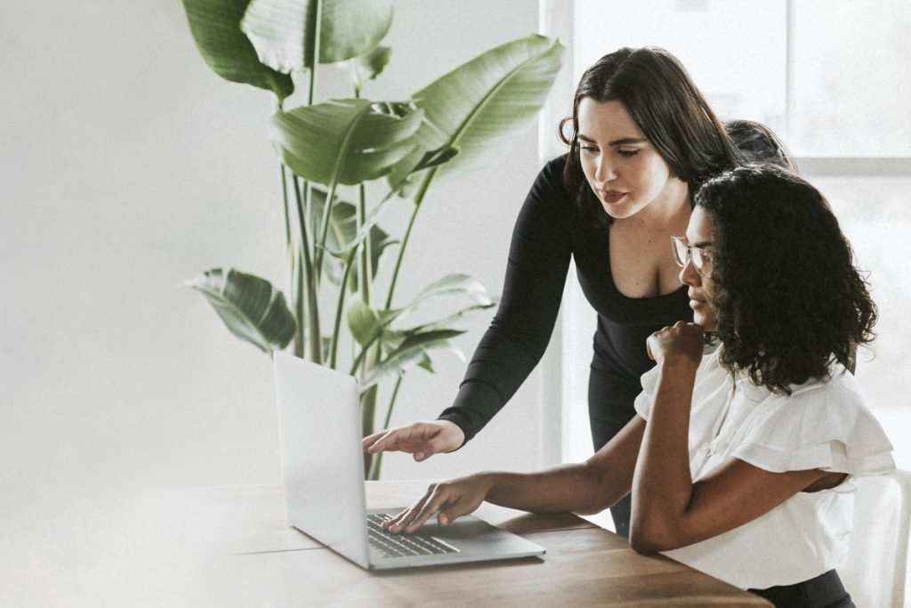 Two women working together at a table among plants, talking through how to describe your vision.