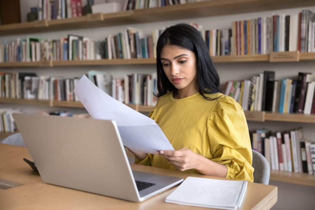 Woman at a laptop holding papers