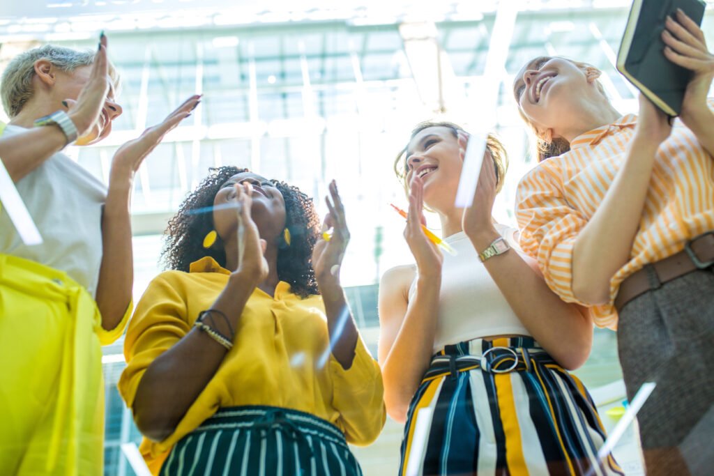 Four women clapping and cheering together, seen from below