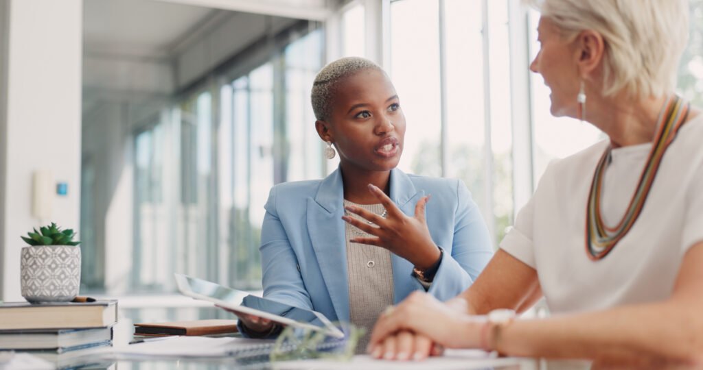 Woman talking with a colleague at a table, weighing whether she should get a business loan.