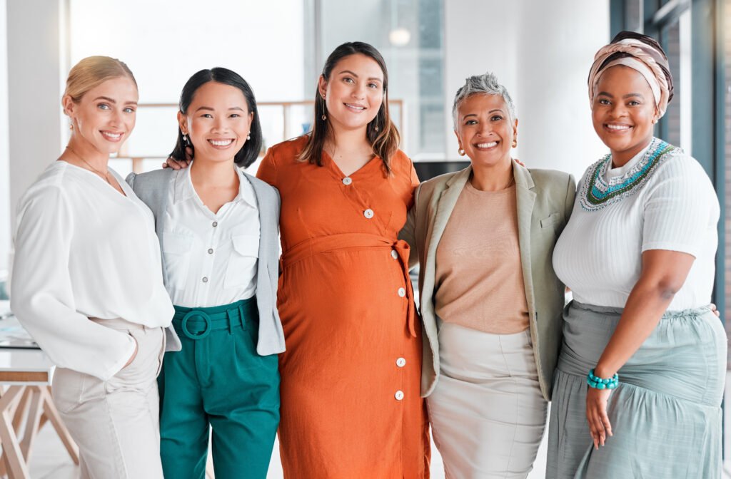 Five smiling women standing arm in arm in a bright office, ready to spring clean their business
