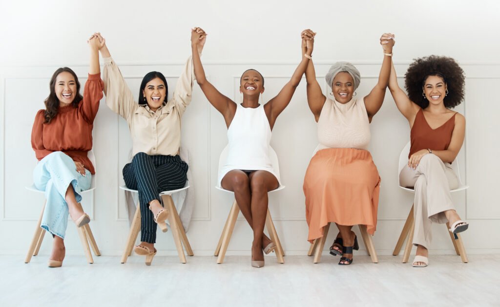 Row of women raising their arms in celebration, the feeling of learning to build wealth as a business owner