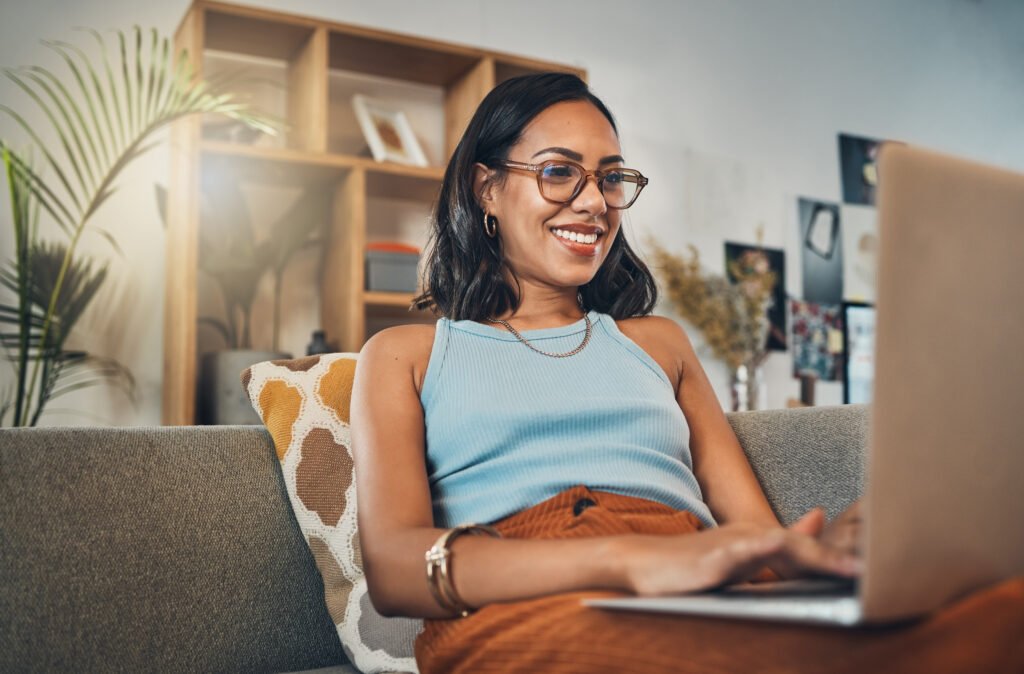 Woman on a couch with laptop, smiling