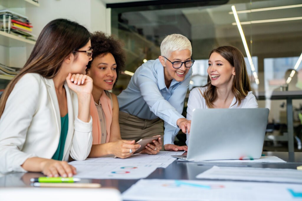 Women at a table with laptops in a meeting, learning to separate business and personal finances
