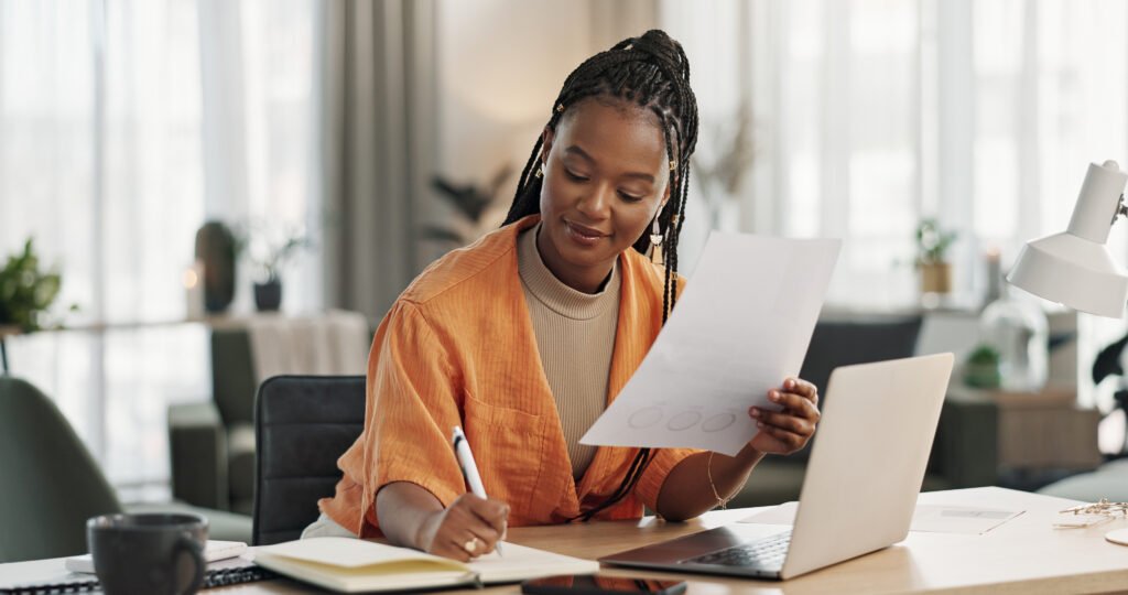 Woman at a laptop with papers, smiling