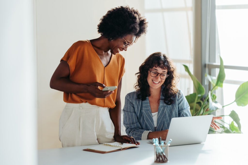 Two women working together at a laptop to create a business budget.