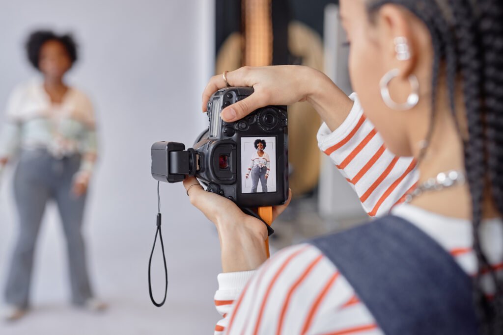 Photographer photographing a woman in a studio, the shot visible on the camera screen, brand photos to build an online presence