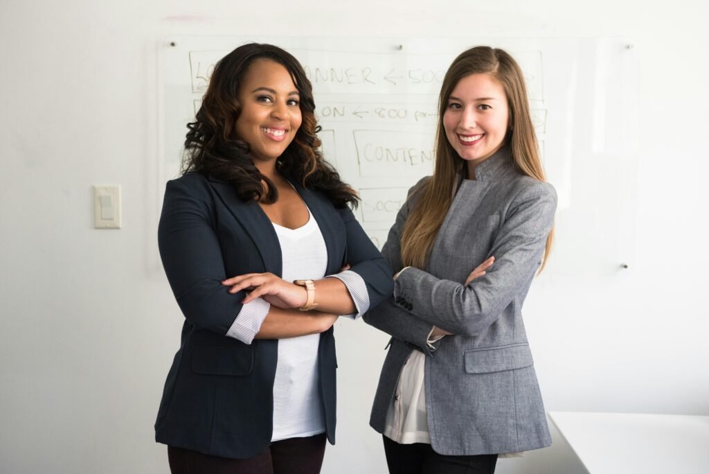 Two confident businesswomen standing with arms crossed, ready to practice the financial habits of wealthy women
