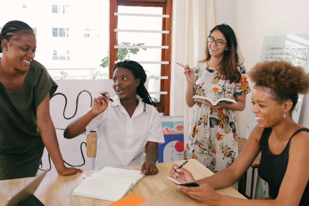 Four women laughing and taking notes around a table in a bright room, calmly planning how to prepare a business for a recession