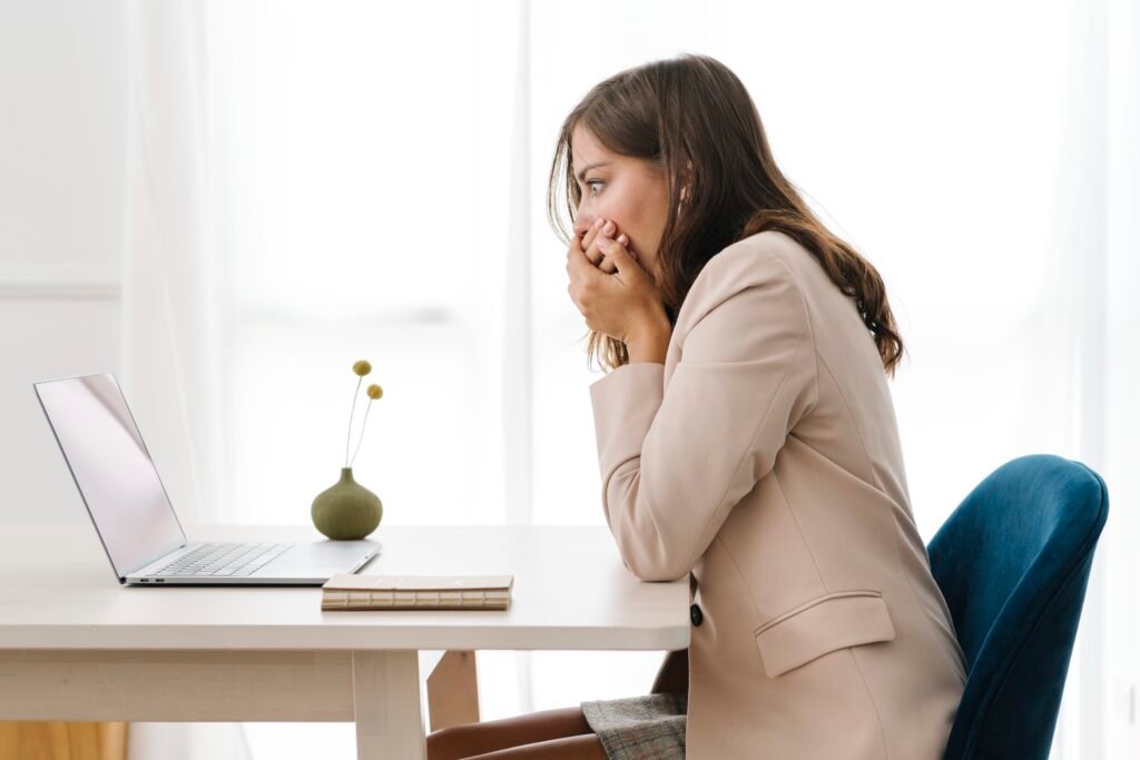 Worried woman with her hands over her mouth staring at her laptop, realizing her prices sit below her break-even rate