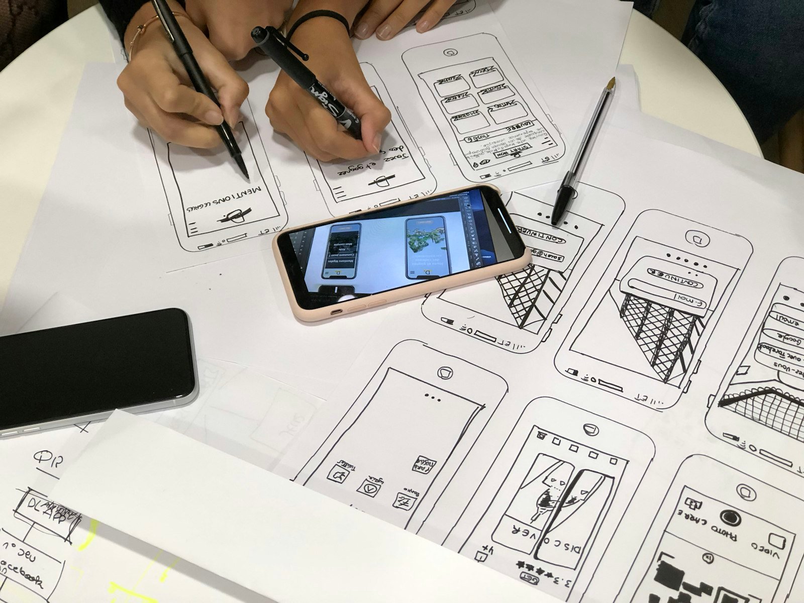Smartphone lying on app wireframe sketches