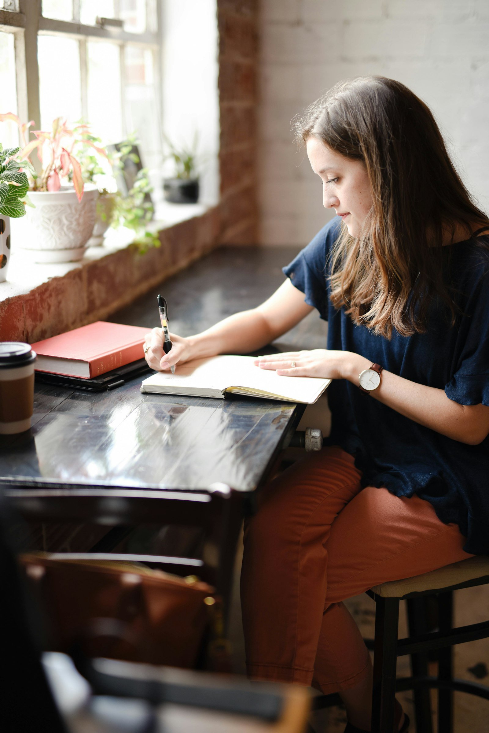 Woman writing in a notebook by a window