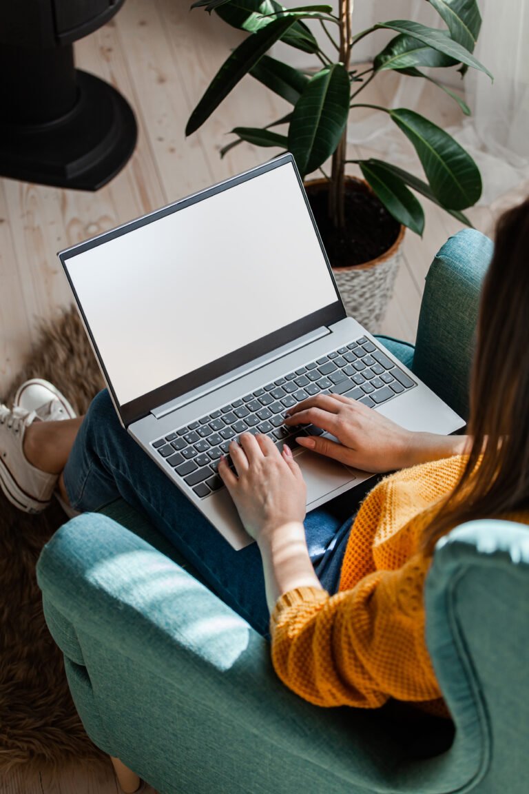 Overhead view of a woman working on a laptop in a green armchair