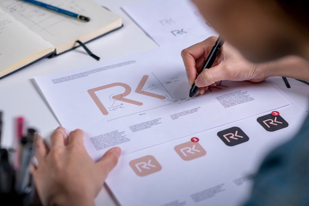 Designer marking up printed logo concepts and app icons with a pen
