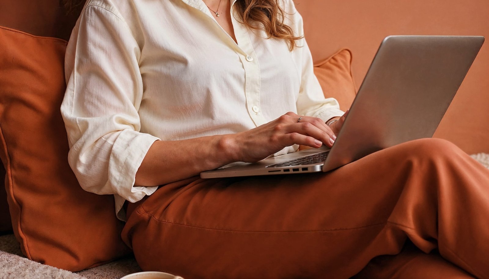 A woman working on her laptop on a cosy couch